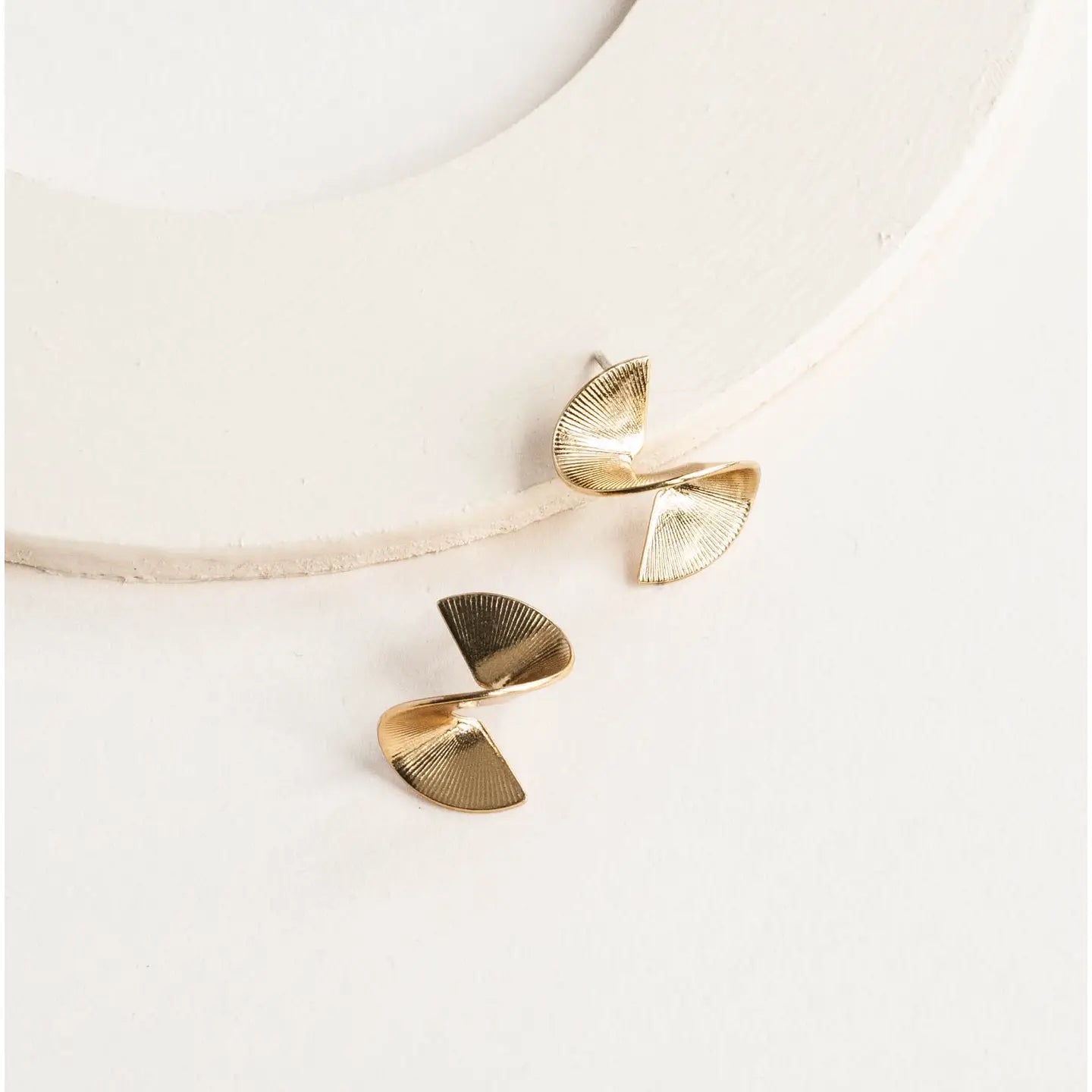 Gold ribbon curled earrings on a white background