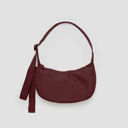Maroon handbag with a strap on a light gray background