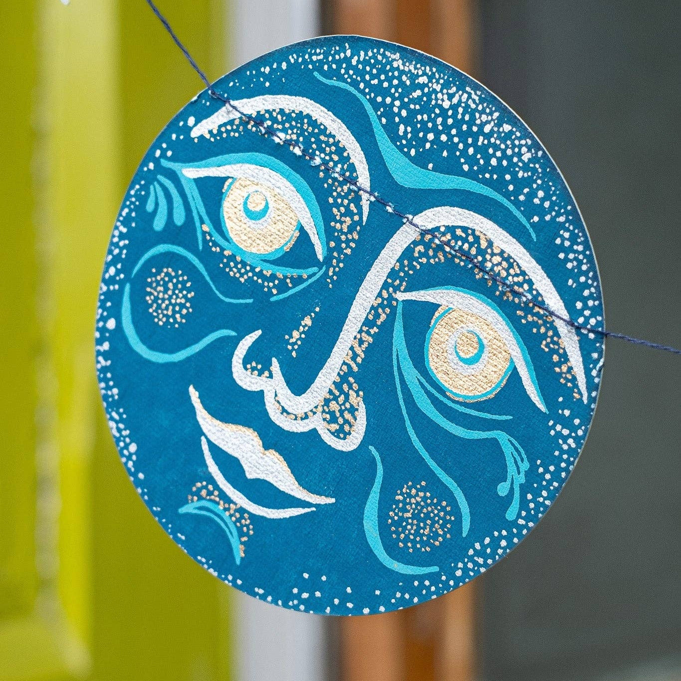 Decorative blue moon paper figure with white designs hanging on a string.
