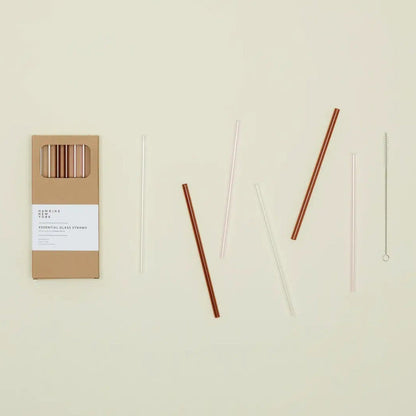 Set of six pink, amber, and clear straws with packaging on a beige background